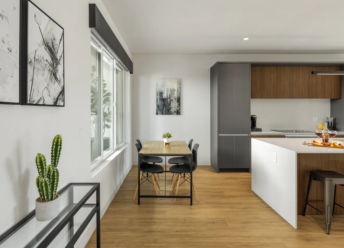 A dining table set in front of kitchen cabinetry and adorned with a cactus centerpiece and wall art. The space radiates warmth and is clearly designed for group meals, casual gatherings, and entertaining guests.