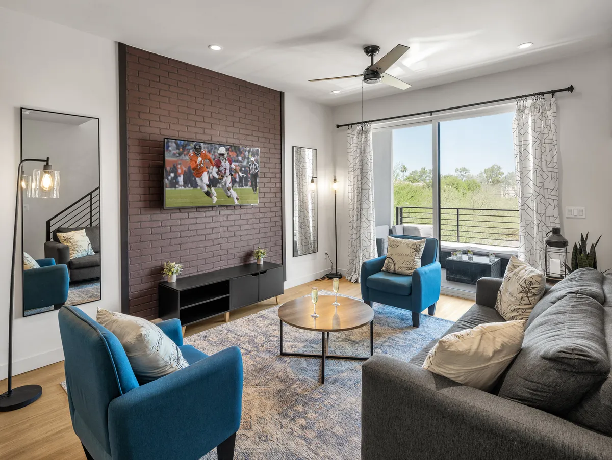 This image captures a contemporary living room with a plush sofa, a modern coffee table, a large TV, and a window offering natural light. The setup exudes comfort and is ideal for socializing, relaxing, or enjoying a movie night.