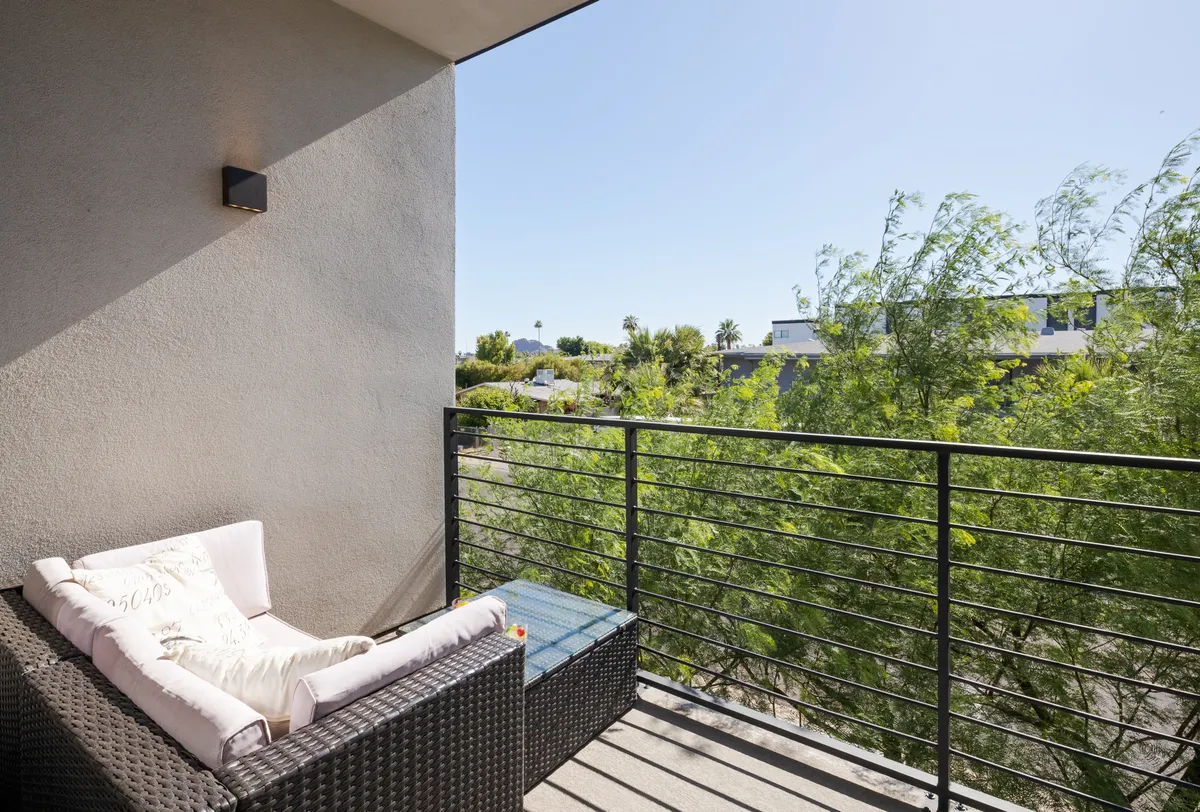 The photo shows balcony seating surrounded by greenery and railings, suggesting a peaceful, private spot for relaxation. The outdoor furniture creates an inviting atmosphere, ideal for both pet owners and their small pets to lounge after returning from adventures.