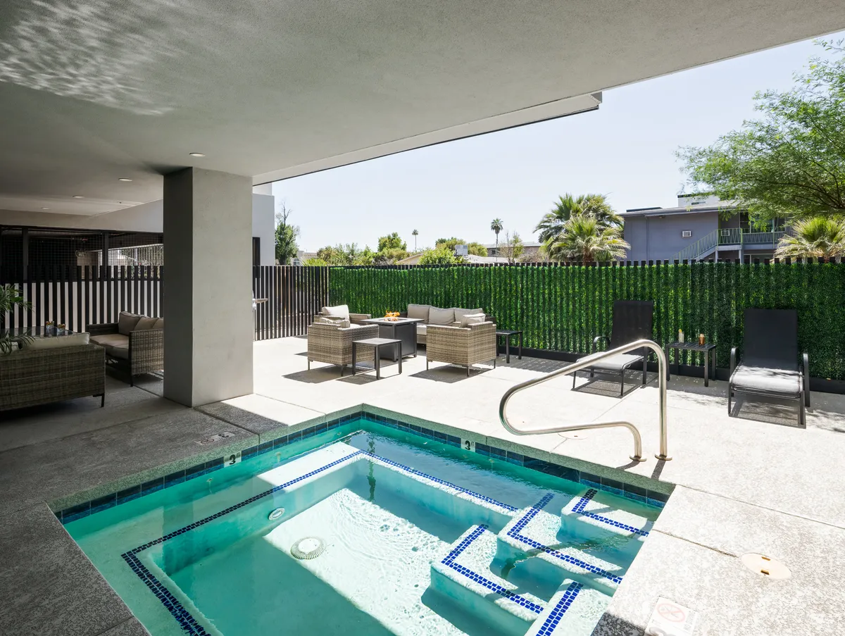 A tranquil outdoor swimming pool area surrounded by greenery, featuring comfortable seating perfect for gatherings or relaxation. The pool is highlighted by the soft glow of sunset, with lounge chairs arranged to invite socializing or unwinding after a busy day.