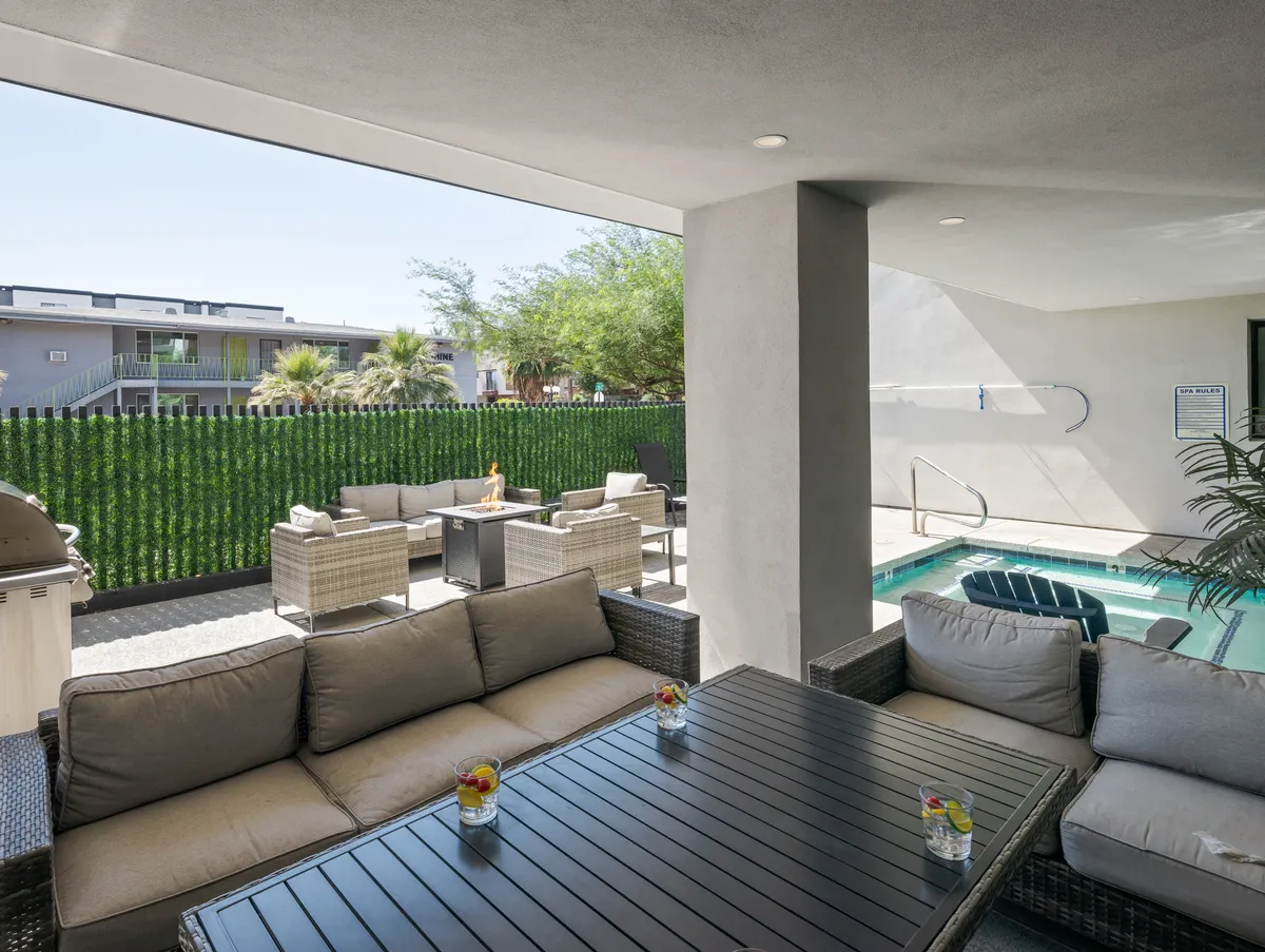 A tranquil, inviting exterior setting featuring an outdoor seating area beside a small pool, surrounded by decorative plants and a table set with drinks. The area appears ready for relaxed social gatherings, intimate conversations, or unwinding after a day of exploring.
