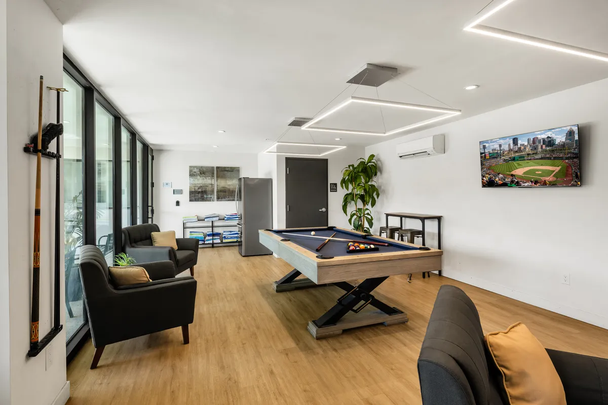 A relaxed, open-concept gathering space with a pool table, plush seating, large windows, and a television, evoking a warm, communal atmosphere ideal for socializing and celebrating.