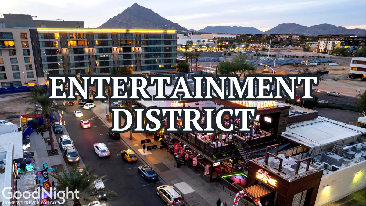 This image captures a bustling entertainment district with prominent signage, a busy street filled with cars, an inviting outdoor dining area, and a backdrop of scenic mountains. The overall atmosphere is energetic, showcasing a vibrant nightlife and social scene.